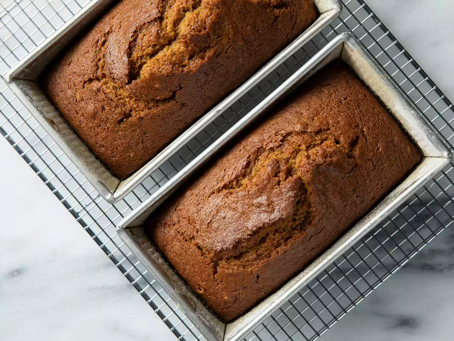 Overhead of two baked pumpkin breads cooling on a wire rack.