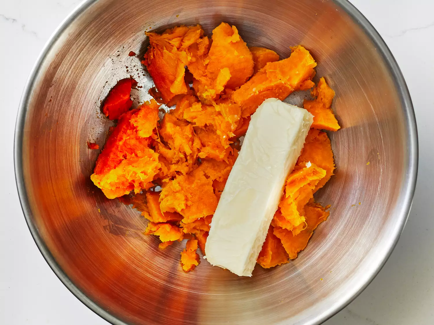 flesh of sweet potato broken apart and placed in a mixing bowl with butter